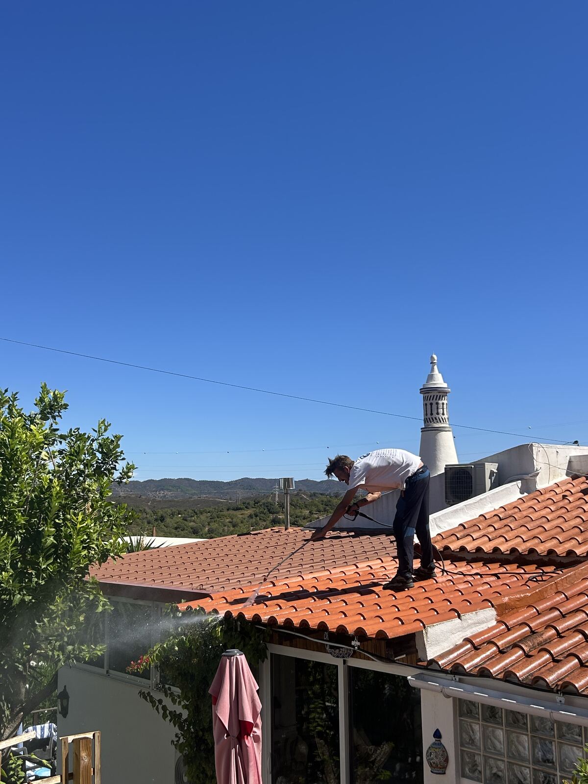 Roof cleaning in progress on a Tavira property with views over the Algarve hills